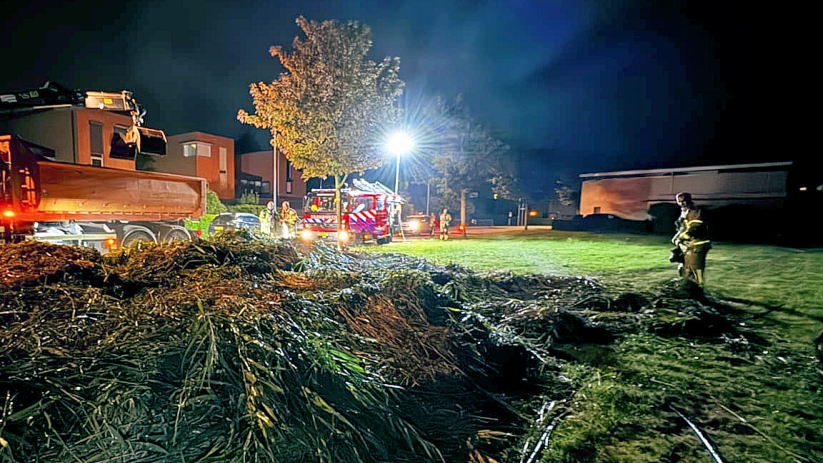 Met behulp van een kraan werd het snoeiafval uit elkaar getrokken.