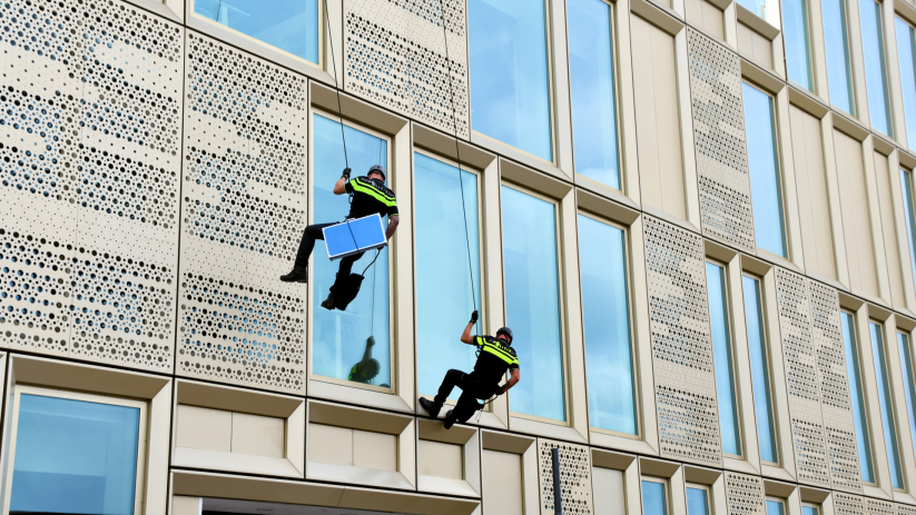 Leden van het Rope Rescue Team abseilden van het gebouw.